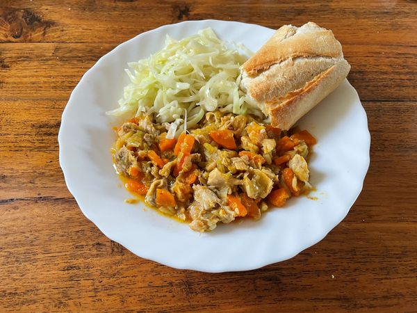 bord met kippenstoof, koolsalade en brood